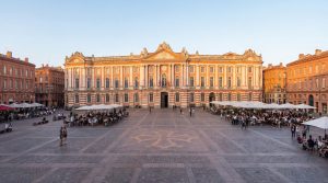 Vue panoramique de la place du Capitole à Toulouse avec ses façades roses emblématiques et ses terrasses animées