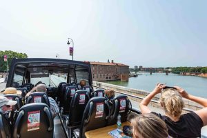 Groupe de touristes souriants en excursion sur le Pont Neuf de Toulouse lors d'un tour